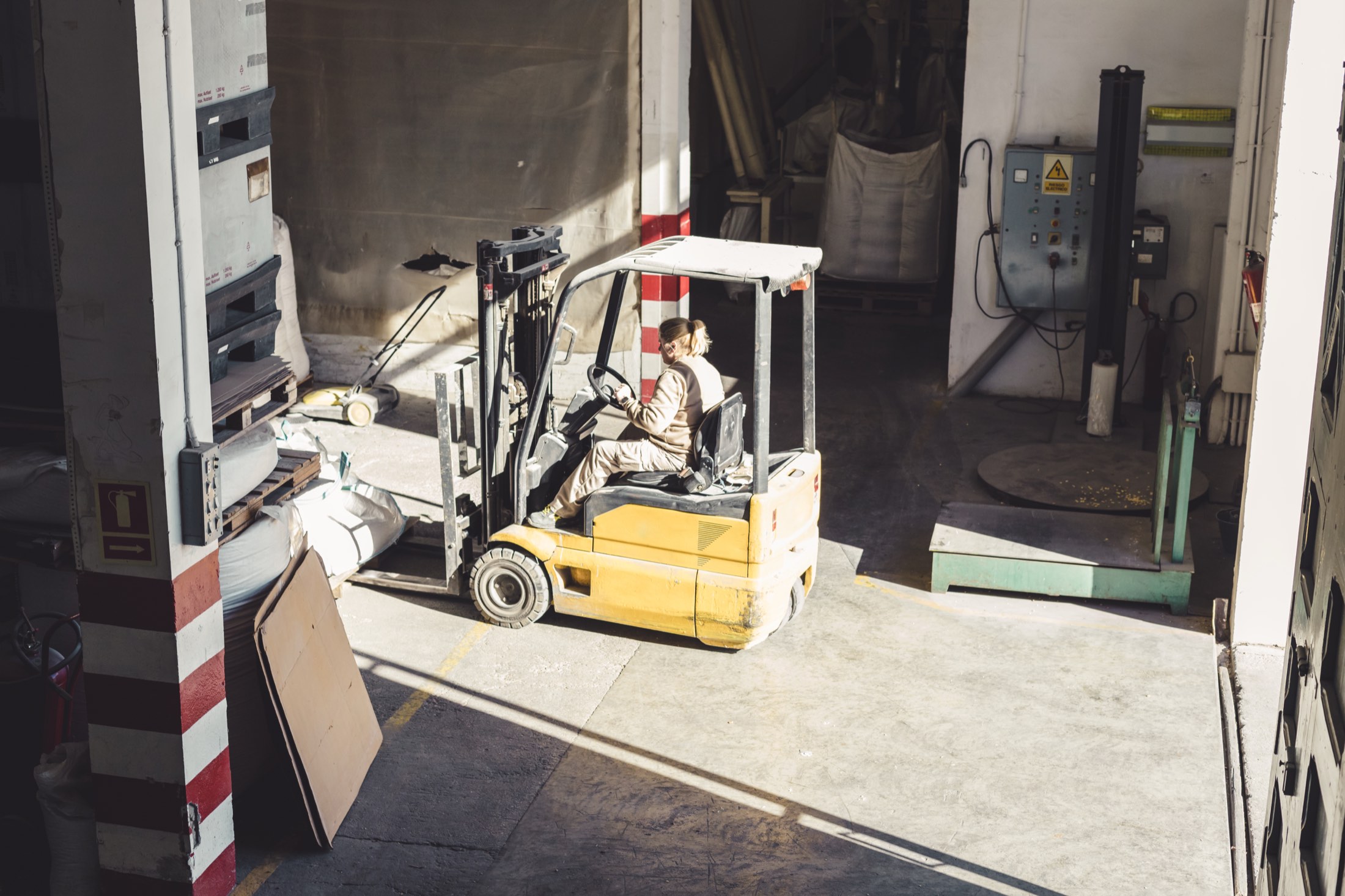 A forklift moving palletised material through a warehouse loading bay.