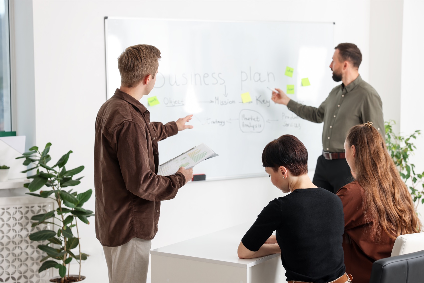 A team working through a business plan mapped out on a whiteboard.